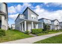 Two-story gray home features a covered porch with modern landscaping and bright green lawn at 4875 Lacewing Dr, Winter Garden, FL 34787