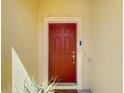 Inviting red front door with a classic design, framed by a light-colored exterior and manicured plants at 509 Artisan St # 43, Orlando, FL 32824