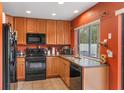 Well-lit kitchen featuring black appliances, granite countertops, and ample cabinet space at 600 Fallsmead Cir, Longwood, FL 32750