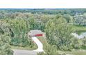 Aerial view of a red house with long driveway surrounded by green trees and a pond at 6144 Avenue G, Mc Intosh, FL 32664