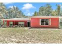 Inviting single-story home with a red exterior, lush plants and white trimmed windows at 6144 Avenue G, Mc Intosh, FL 32664