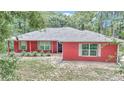 Charming red single-story home featuring well-maintained landscaping and inviting curb appeal at 6144 Avenue G, Mc Intosh, FL 32664