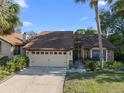 Inviting one-story home featuring a well-maintained lawn, mature trees, and a two-car garage at 7027 Villa Estelle Drive, Orlando, FL 32819