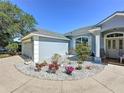 Single-story house featuring a circular driveway with white gravel and decorative landscaping, flower beds, and flowering plants at 827 Princeton Dr, Clermont, FL 34711