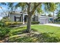 Beautifully landscaped home exterior displaying a lush green lawn, mature trees, and a three-car garage at 849 Shadowmoss Dr, Winter Garden, FL 34787