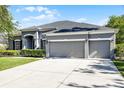 Inviting home featuring a manicured lawn and a spacious driveway leading to a three-car garage at 849 Shadowmoss Dr, Winter Garden, FL 34787
