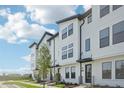 Townhome featuring white painted brick and siding with modern dark window frames and awnings at 15489 Hamlin Park Drive, Winter Garden, FL 34787