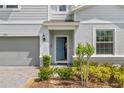 Charming home featuring a beautiful entryway with a blue front door, lush landscaping, and an attached garage at 1970 Summer Dr, Davenport, FL 33897