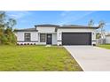 Charming single-story home featuring a well-manicured lawn, a gray garage door and black trim at 236 Marion Oaks Mnr, Ocala, FL 34473