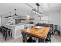 Open floorplan combining a stylish kitchen with breakfast bar and dining area with a rustic wooden table at 25931 Azalea Ln, Astatula, FL 34705