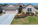 Charming single-story home featuring a two-car garage, brick walkway, and vibrant flower beds at 2977 White Cedar Cir, Kissimmee, FL 34741