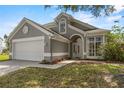 Attractive gray home featuring a two-car garage, arched entry, and manicured front lawn at 3660 Ventura Club Cir, Orlando, FL 32822