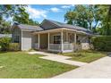 Quaint one-story home featuring a welcoming covered porch, well-maintained lawn, and beautiful landscaping at 441 S Blue Lake Ave, Deland, FL 32724