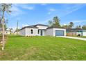 View of a well-maintained home with a green lawn, painted in neutral colors and a blue garage door at 443 Marion Oaks Crse, Ocala, FL 34473