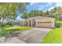Charming single-story home featuring a manicured lawn, two-car garage, and welcoming front entrance at 572 Lanarkshire Pl, Apopka, FL 32712