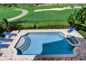 Beautiful pool with an integrated spa, surrounded by lush landscaping and comfortable lounge chairs at 7388 Gathering Ct, Reunion, FL 34747