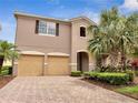 Charming two-story home featuring a two-car garage, brick paved driveway, and tropical landscaping at 11885 Padua Ln, Orlando, FL 32827