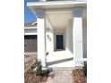 Stylish blue front door with white pillars supporting the covered front porch and attractive landscaping at 1374 Brentwood Dr, Kissimmee, FL 34746