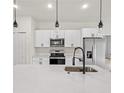 Kitchen with stainless appliances, quartz countertops, white cabinets and stylish lighting at 14961 Sw 38Th Cir, Ocala, FL 34473