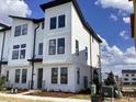 New townhouse with white siding, black trim, and a modern design under a sunny blue sky at 15483 Hamlin Park Drive, Winter Garden, FL 34787