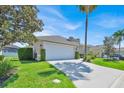 Well-maintained home featuring a lush green lawn, mature trees, and a spacious two-car garage at 162 Plumoso Loop, Davenport, FL 33897