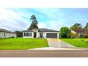 Charming single-story home featuring a gray roof, a gray garage door, and a beautifully landscaped front yard at 492 Marion Oaks Mnr, Ocala, FL 34473