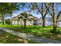 Spacious backyard with lush lawn, mature trees, and screened in patio at 581 Hollingshead Loop, Davenport, FL 33896