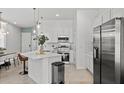 Modern kitchen with stainless steel appliances, white cabinetry, and a breakfast bar that connects to the dining area at 10436 Ebb Tide Lane, Orlando, FL 32821
