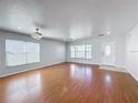 Spacious and bright living room with hardwood flooring, large windows, and a modern ceiling fan at 1176 Liberty Hall Dr, Kissimmee, FL 34746