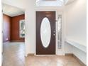 View of the foyer with tile flooring, shelving, and a decorative oval-windowed door at 12213 Bohannon Blvd, Orlando, FL 32824