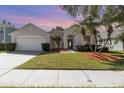 Charming single-story home featuring a well-manicured lawn, palm trees, and a two-car garage at 12213 Bohannon Blvd, Orlando, FL 32824