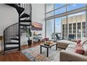 Inviting living room with spiral staircase, hardwood floors, stylish rug, comfortable sofa, and large windows at 150 E Robinson St # 1219, Orlando, FL 32801
