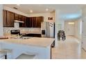 Well-lit kitchen with dark cabinetry, stainless steel appliances, and a breakfast bar at 156 Eagleview Loop, Davenport, FL 33837