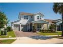 Two-story house featuring a two-car garage, front porch with swing, manicured lawn, and brick-paved driveway at 18907 Rawson St, Orlando, FL 32827