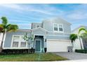 Well-kept blue home featuring a two-car garage, manicured lawn, and bright natural lighting at 2123 Lelani Cir, Davenport, FL 33897