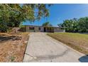 Exterior showcasing the front view of a single-story home with a concrete driveway and landscaping in a sunny environment at 5201 Palisades Dr, Orlando, FL 32808