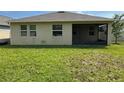 View of the home's back exterior, with a screened in porch and a spacious lawn at 5550 Bakewell Pl, St Cloud, FL 34771