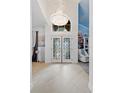 Elegant foyer with tiled floor, double doors, and a dazzling crystal chandelier at 8453 Firefox Cv, Orlando, FL 32835
