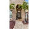 Inviting front entry featuring brick archway, double doors, and lush tropical landscaping at 8453 Firefox Cv, Orlando, FL 32835