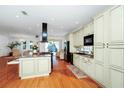 Spacious kitchen with wood flooring, a central island with bar seating, and sleek black appliances at 11718 Fitzgerald Butler Rd, Orlando, FL 32836