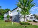 Modern two-story townhome featuring a gray garage door and a well-manicured front lawn and a brick driveway at 1628 Little Wren Ln, Winter Park, FL 32792