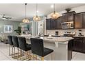 Modern kitchen with granite countertops, stainless steel appliances, dark cabinets, and stylish pendant lighting at 2036 Lelani Cir, Davenport, FL 33897