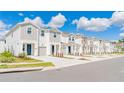 Row of charming townhomes with neutral paint, attached garages, landscaping, and blue sky with clouds at 2413 Brook Marsh Loop, Kissimmee, FL 34747