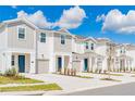 Charming townhomes with neutral paint, attached garages, professional landscaping under a blue sky with puffy clouds at 2413 Brook Marsh Loop, Kissimmee, FL 34747