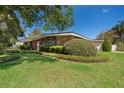 Lovely brick home featuring neatly trimmed hedges, a green lawn, and an American flag by the front door at 2609 Chinook Trl, Maitland, FL 32751