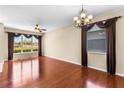Spacious living room featuring hardwood floors, decorative chandelier, and large windows with stylish curtains at 4027 Sunrise Ridge Blvd, Groveland, FL 34736
