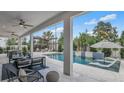 Inviting covered patio overlooks a modern pool with integrated lounge chairs and a pergola covered outdoor seating area at 52 Overleaf Ln, Orlando, FL 32839
