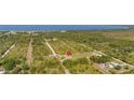 Expansive aerial view of a home surrounded by lush greenery, a road, and a serene lake in the background at 6273 Toronja Dr, Indian Lake Estates, FL 33855