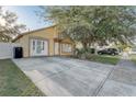 Inviting yellow home with a well-maintained lawn, wide driveway, and an attached front entry at 9447 Dearmont Ave, Orlando, FL 32825
