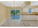 Bright kitchen featuring white cabinets, granite countertops, tile flooring, and access to the patio at 1001 Dora Ave, Tavares, FL 32778